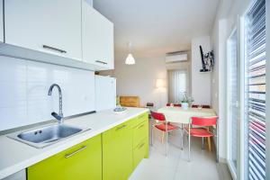 a kitchen with yellow cabinets and a table with chairs at Villa Grdelina in Supetar