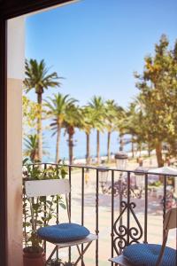 a balcony with two chairs and palm trees on a beach at Balcon de Europa in Nerja
