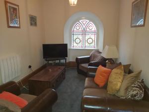 a living room with a couch and a tv and a window at Kirkhouse in Wick