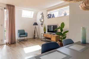 ein Wohnzimmer mit Tisch und Stühlen und einem Fernseher in der Unterkunft Boutique resort Schaardijk vakantieappartement in Scharendijke