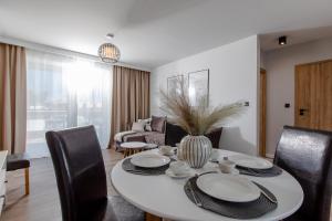 une salle à manger avec une table et des chaises blanches dans l'établissement Resort Apartamenty Klifowa Rewal 65, à Rewal
