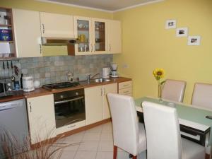 a kitchen with white cabinets and a table with chairs at Holiday Home Krasica in Bakar