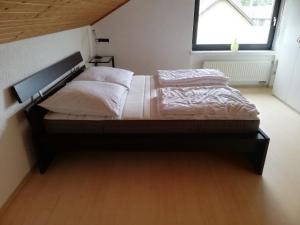 1 cama con sábanas y almohadas blancas en una habitación con ventana en Ferienwohnung / Monteurswohnung in ruhiger Waldlage en Borghees