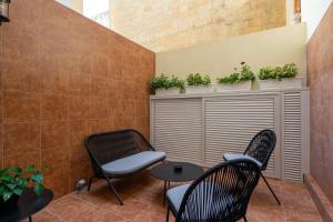 a patio with two chairs and a table and some plants at Lady Todd in Sliema
