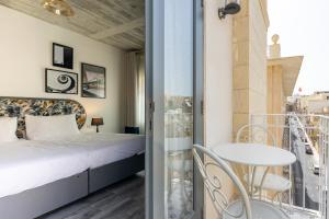 a bedroom with a bed and a balcony with a table at Lady Todd in Sliema