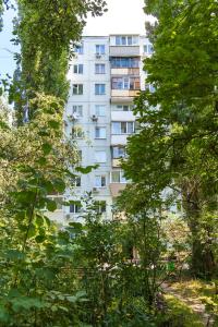 a tall white building in the middle of trees at Апартаменти MYFREEDOM поруч із метро Кловська in Kyiv