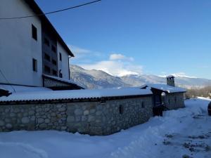 un edificio en la nieve con montañas en el fondo en Къща за гости "Тони" en Dobrinishte