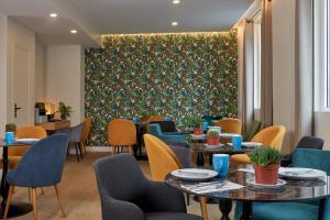 Un restaurante con mesas y sillas y una pared verde. en Hotel Apolonia Paris Montmartre; Sure Hotel Collection by Best Western, en París