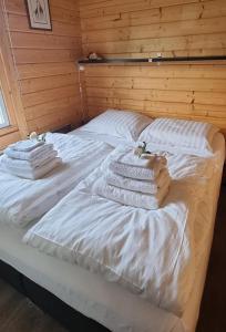 a bed with white blankets and towels on it at Prachtig Scandinavisch Chalet in Makkum