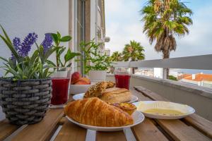 a table with plates of bread and drinks on a balcony at Paz & Amor Flat Nazaré - Peace & Love in Nazaré