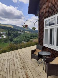 una terraza de madera con mesa y sillas en un edificio en Cabana de pe stanca - hotel en Cîrlibaba Nouă