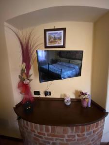 a living room with a tv and a brick fireplace at Orchidea in Carrù