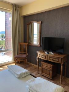 a bedroom with a tv and a desk with a television at Family Hotel Littoral in Sozopol