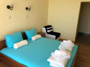 een slaapkamer met een blauw bed met blauwe kussens en een stoel bij Family Hotel Littoral in Sozopol