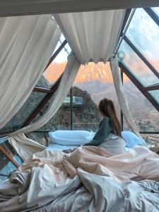 a woman sitting on a bed in a tent at Vertical Sky Luxury Suites in Ollantaytambo