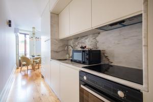 uma cozinha com armários brancos e um forno de fogão preto em Douro Golden Studio em Porto
