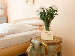 a vase of flowers on a table next to a bed at Apartmá Marie 1880 in Karlovy Vary