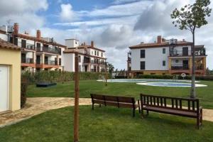 a park with two benches in the grass with buildings at Playa, Golf y Montaña. Dos países, un lugar único. in Huelva