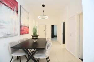 uma sala de jantar com uma mesa preta e cadeiras brancas em City center luxury apartment in Netanya em Netanya