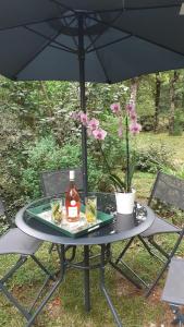 a table with a bottle of alcohol on it under an umbrella at La Bergerie in Lagarrigue