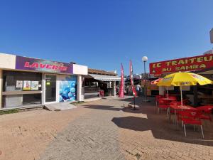 een groep tafels en stoelen met parasols op straat bij CHARMANT studio proche de la mer in Le Grau-du-Roi