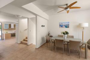 a dining room with a table and chairs and a ceiling fan at Villa Aegean Blue View with Private Pool and Seaview in Lindos