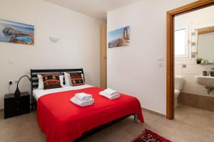 a bedroom with a red bed and a bathroom at Villa Aegean Blue View with Private Pool and Seaview in Lindos