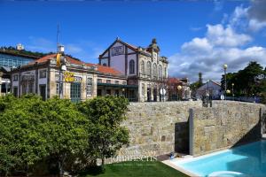 un gran edificio detrás de una pared de piedra con piscina en Casa Melo Alvim - by Unlock Hotels, en Viana do Castelo