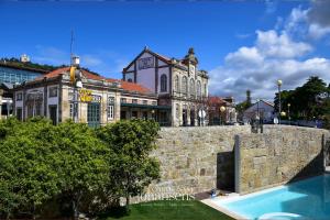 a large building behind a stone wall with a swimming pool at Casa Melo Alvim - by Unlock Hotels in Viana do Castelo
