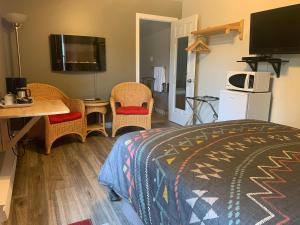 a room with a bed, chair, desk and television at Motel Des Cascades in Baie-Saint-Paul