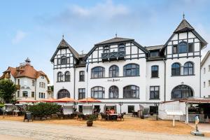 a large white building with tables in front of it at Hotel Asgard in Zinnowitz