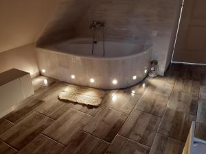 a bath tub in a bathroom with a wooden floor at FLÓRA VENDÉGHÁZ A BALATONNÁL in Lovas