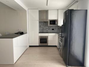 een keuken met witte kasten en een zwarte koelkast bij Apartamento Andalucía Centro in Antequera