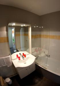 een badkamer met een wastafel, een bad en een spiegel bij Appart'hotel Les Palatines in Saint-Étienne