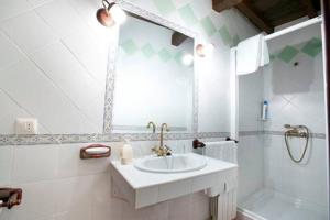 Baño blanco con lavabo y espejo en CASA RURAL LOS PORTALES Valle del Jerte, en Cabezuela del Valle