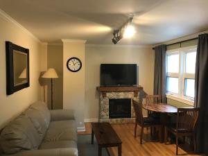 sala de estar con sofá, TV y chimenea en Canadian Rockies Inn - Adults only, en Field