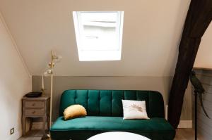a green couch in a room with a window at Rempart Doré in Saint Malo