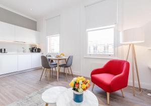 ロンドンにあるWhite Piccadilly Luxury Flatのリビングルーム(赤い椅子、テーブル付)