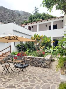 a patio with a table and an umbrella and a building at Casa la plaza in Agulo