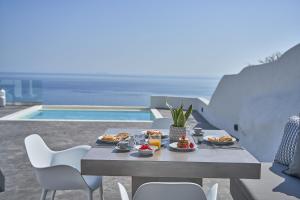 a table with food on it next to a pool at Topos Exclusive in Imerovigli