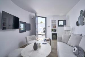 a white living room with a couch and a table at Topos Exclusive in Imerovigli