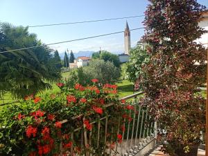 Cassacco的住宿－NICOLE COUNTRY APARTMENTS，一座种有红色花卉和教堂的花园