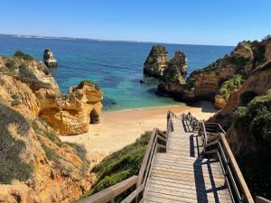 una escalera de madera que conduce a una playa con rocas en Terraço e Mar, en Alvor