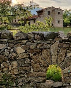 una pared de piedra frente a una casa en LA SOLANILLA -Casas Rurales, en Torre Val de San Pedro
