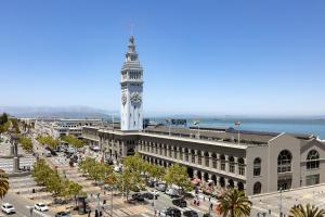 a large building with a clock tower in front of the ocean at 1 Hotel San Francisco in San Francisco