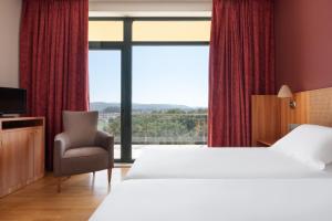 a hotel room with a bed and a chair and a window at Exe Vía Argentum in Silleda