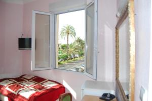 Cette chambre dispose d'une fenêtre avec un lit et une table. dans l'établissement Hôtel Azur, à Nice
