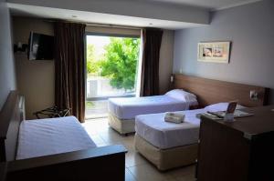 a hotel room with two beds and a window at Apart Hotel Rivadavia 815 in Neuquén