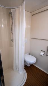 La salle de bains blanche est pourvue d'une douche et de toilettes. dans l'établissement Gipsy Home, à Nieuwleusen