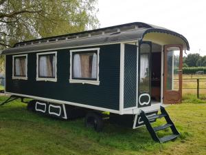 une remorque noire et blanche garée dans l'herbe dans l'établissement Gipsy Home, à Nieuwleusen